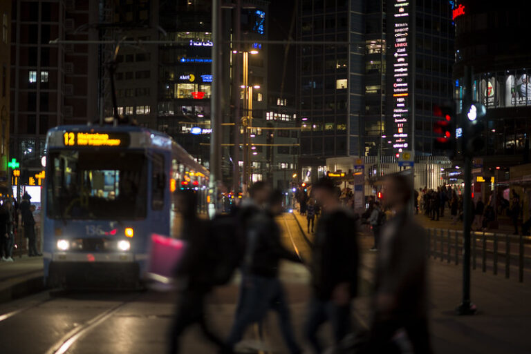 Illustrasjonsbilde av vennegjeng som krysser gaten ved Jernbanetorget Oslo med en trikk i bakgrunn.